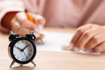 alarm clock with time running out. Students hands to take exams, write examination room with pencil...