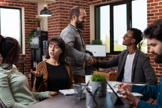 Businessman shaking hand with manager during business meeting in startup office. Multi-ethnic businesspeople discussing company turnover working at marketing strategy brainstorming ideas
