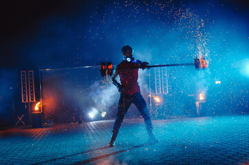 A fire show, dancing with a flame, a masculine master juggling with a firework. Film noise.