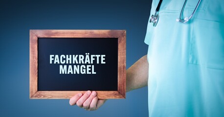 Fachkräftemangel (medizinisches Personal). Arzt zeigt Schild/Tafel mit Holz Rahmen. Hintergrund...