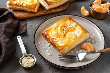 Mini puff pie with cheese cream, almonds, and tangerines in a plate on the kitchen table. Delicious...