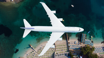 Aerial top down view of an airplane flying over blue sea as a travel concept with copy space