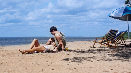 Fototapeta na wymiar Smiling woman lying near boyfriend in sunglasses on beach