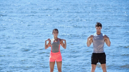 Young brunette couple training near sea on beach