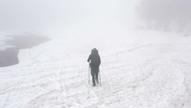 Solitary hiker walking alone in the snow in cold wintry wilderness