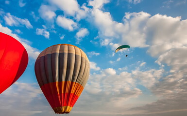 Balloon and paraglider on the background of blue sky with white clouds in summer