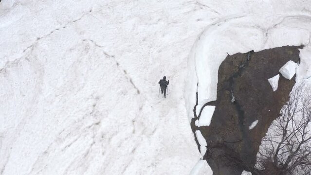 Solitary hiker walking alone in the snow in cold wintry wilderness