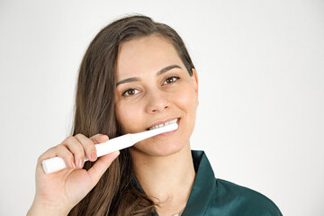 A young attractive girl of Caucasian appearance brushes her teeth with an ultrasonic brush. Vibrobrush for teeth. Morning hygiene. hygiene procedures. Morning rituals. Teeth cleaning.