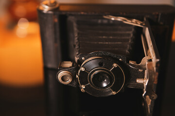 Vintage photo camera and its reflection on an interior deco setup with an old lamp in background.