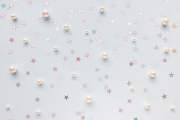 Trendy silver foil confetti stars and white pearls on blue background. Festive abstract background. Birthday party, New Year, Christmas celebration, holidays, winter and dreams concept