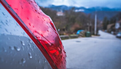 Rear light of a subcompact car in the rain, in winter, italy