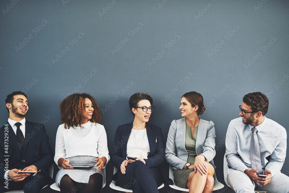 Poster connecting before theyre called in. studio shot of a group of businesspeople talking while waiting i