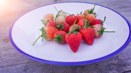 fresh red strawberries on a white plate placed on a wooden background healthy fruit high in vitamins.