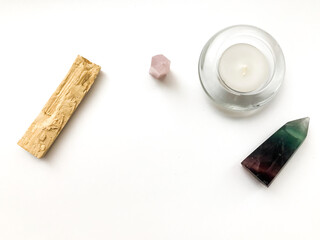 Palo santo incense stick for meditation, candle and rose quartz crystal on a white background,...