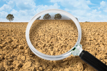 Plowed field ready to be sown with trees on backgound and cloudy sky - Concept seen through a...