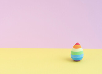 cosmetic sponge in the form of an easter egg on a yellow-pink background. copy space.