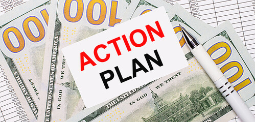 Against the background of reports and dollars - a white pen and a card with the text ACTIOON PLAN. Business concept