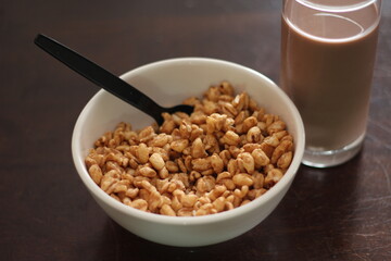 cereal in a white cup with chocolate milk in a ready-to-eat glass Served on a brown wooden table.