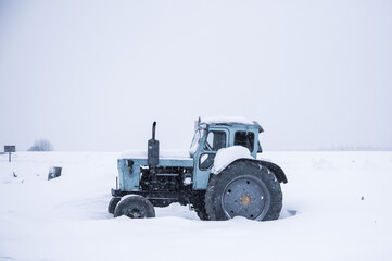 Tractor on a snow-covered field against a cloudy sky.