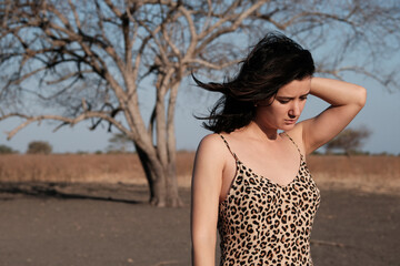 Beautiful woman wearing leopard slip dress in savanna enjoying freedom and nature scenery