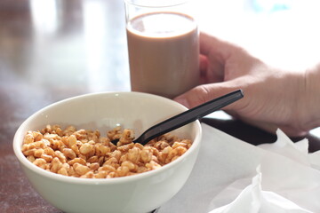 cereal in a white cup with chocolate milk in a ready-to-eat glass Served on a brown wooden table.