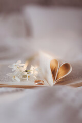 Fototapeta na wymiar Wedding golden ring and open book with folded sheets in heart shape. Wedding concept