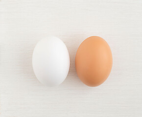 two Easter eggs white and brown on a white wooden background, close up. copy space.