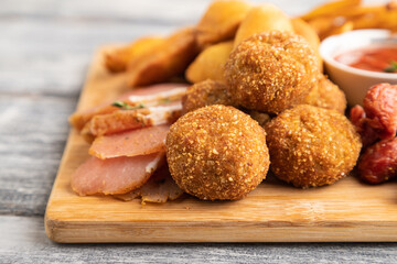 set of snacks: sausages, fried potatoes, meat balls, dumplings, basturma. Side view, selective focus.