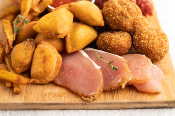 set of snacks: sausages, fried potatoes, meat balls, dumplings, basturma. Side view, selective focus.