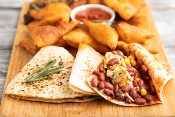 set of snacks: nachos, chicken wings, fried ribs, bean tortillas. Side view, selective focus.