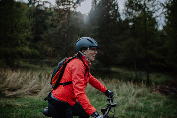 Active senior woman biker riding bike in nature on autumn day.