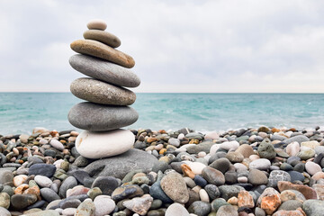 Pyramid stones balanced on the beach. The object is in focus, the background is blurred.