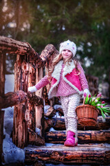 Baby in the winter forest. Girl on a wooden bridge. Baby in winter coat. Girl in early spring. Beautiful girl with long hair in a hat. Girl with a basket of tulips. girl smelling flowers