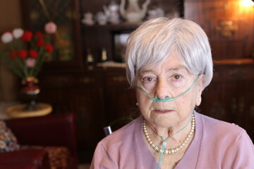 Senior woman using nasal cannula due to lack of oxygen - obrazy, fototapety, plakaty