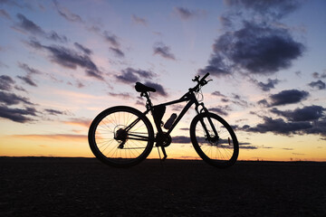 Fototapeta na wymiar Bicycle silhouette at sunset against the evening sky