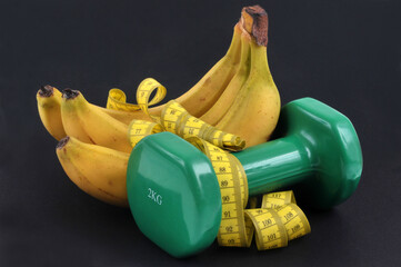 Concept de régime bananes avec un mètre souple et une haltère sur un fond noir
