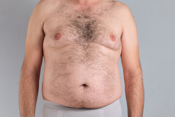 Fat hairy belly of a caucasian man isolated on grey background, no faces are shown