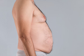 Profile view of the hairy belly of a caucasian man, vertical photo, isolated on gray background,...