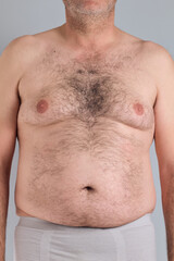 Naklejka premium Fat hairy belly of a caucasian man isolated on grey background, no faces are shown, close up, nudity shown