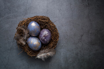 Easter card with a copy of the place for the text. Purple, blue and golden eggs with lavender on a dark background. The purple hue trend of 2022 is very relevant. Natural dye karkade tea. Top view.