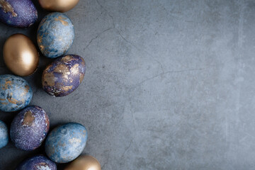 Easter card with a copy of the place for the text. Purple, blue and golden eggs on a dark background. The trend of 2022 purple shade is very peri. Natural dye karkade tea. Top view.