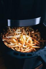 Air fryer with french fries on the worktop