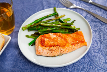 Fresh salmon steak with bunch of roasted asparagus on table.