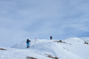 Fototapeta na wymiar Snowshoe hikers on a marked trail towards mount Darlux in Berguen, Switzerland