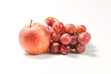 Still life of red grapes and red apple with water drops on a light background.
