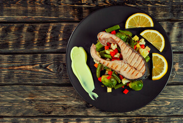 Grilled salmon steak. Red salmon with lemon and vegetables close up. wasps on a salad of boiled cabbage, carrots, green peas and broccoli. Copy space and free space for text near food.