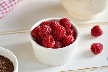 Fresh ripe raspberries in a bowl, with linseeds in the foreground