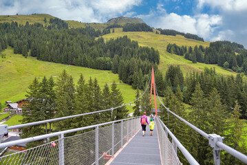 Frau mit Kind wandert über Hängeseilbrücke im Talschluss bei Saalbach Hinterglemm in Österreich