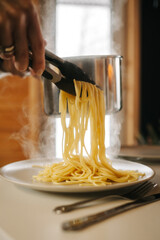 The girl puts spaghetti. Steam is coming. Close up