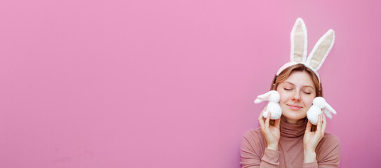 Beautiful young woman with bunny ears on pink background. Handmade Easter decoration. Horizontal banner with copy space